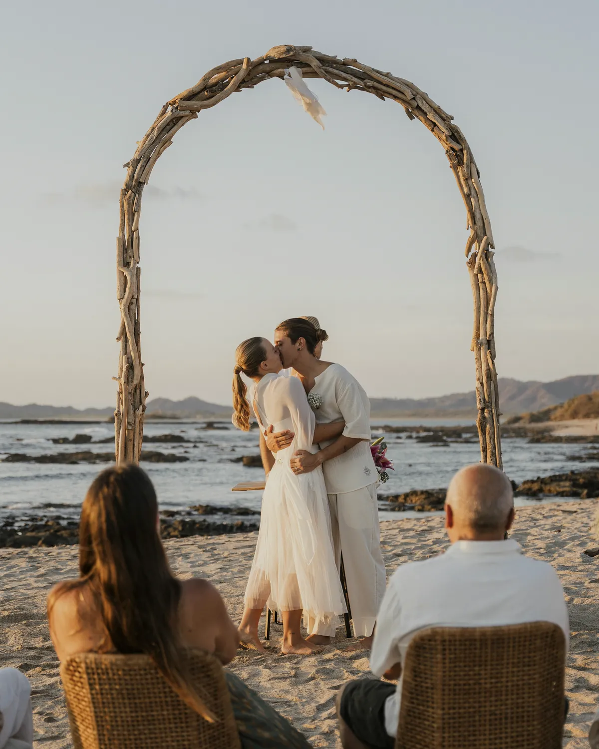Ceremonia en la playa bajo el arco móvil de madera de mar