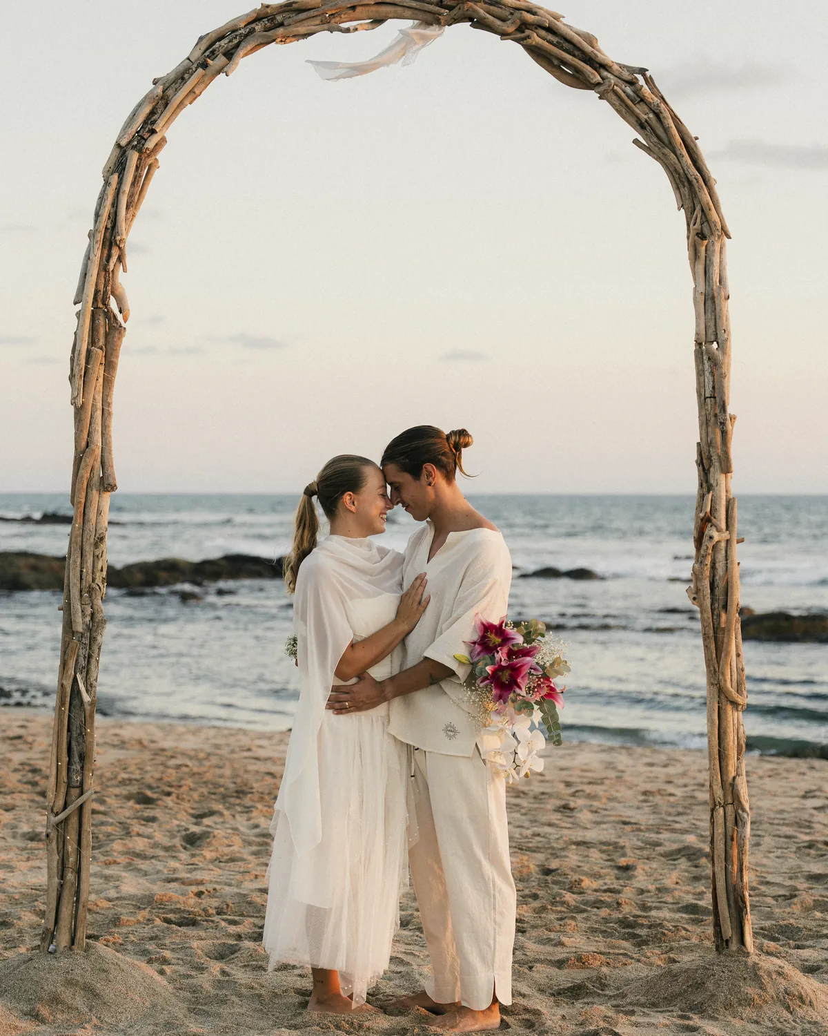 Pareja bajo el arco móvil de madera de mar al atardecer