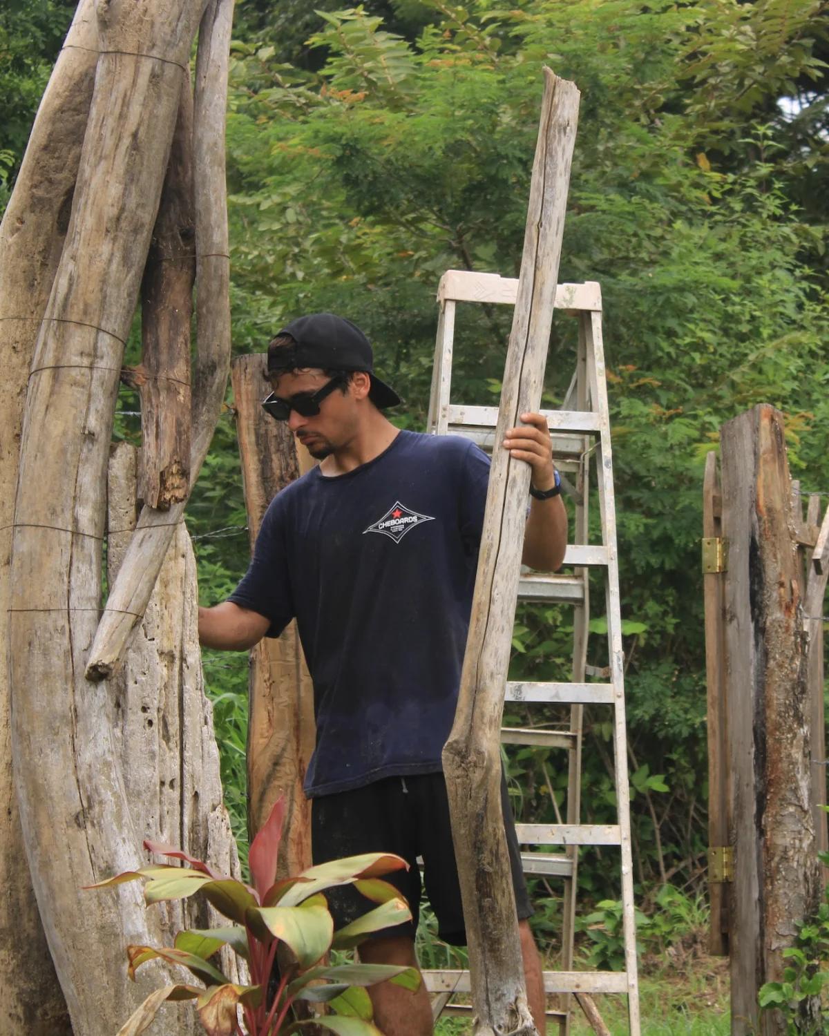 Santiago Imberti con una rama de madera de mar junto a la escalera, armando el portal del bosque